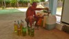 Un vieil homme remplit des bouteilles d'essence pour les revendre la nuit, vers Kratie, Cambodge